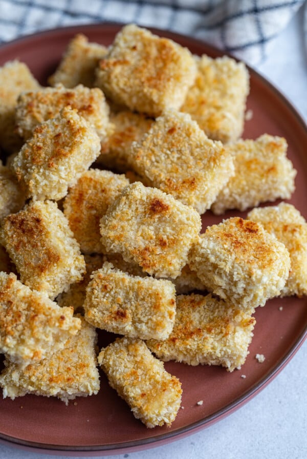 panko crusted tofu cubes on a dark red plate