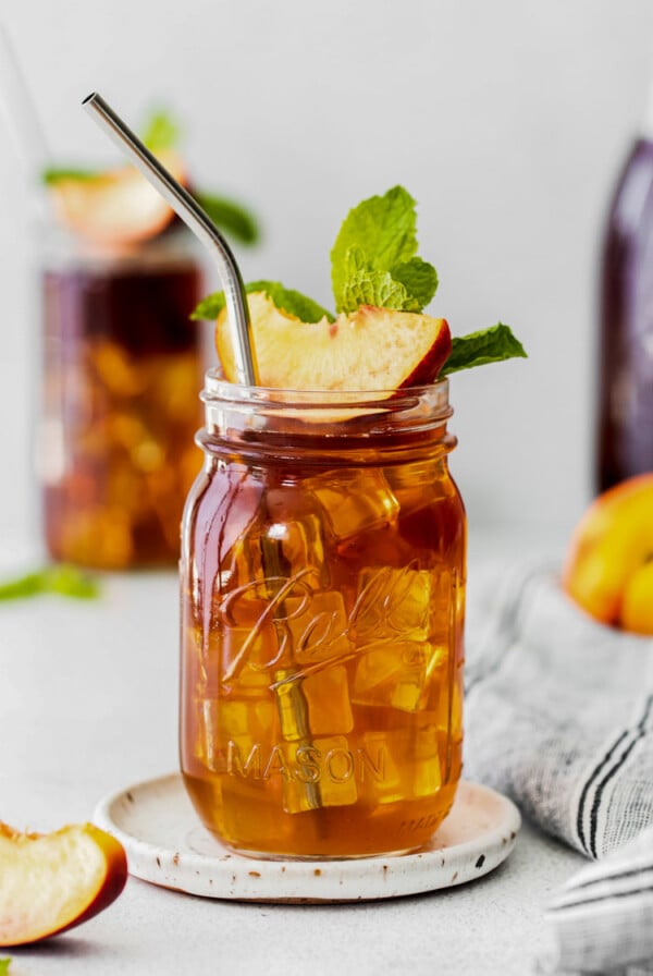 peach iced tea served in a mason jar with a peach slice