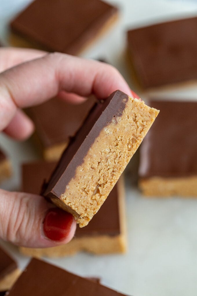 hand holding up a chocolate peanut butter bar with more in the background