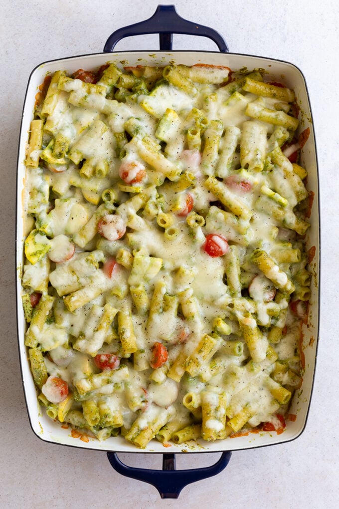 casserole dish loaded with pesto pasta and topped with melted cheese