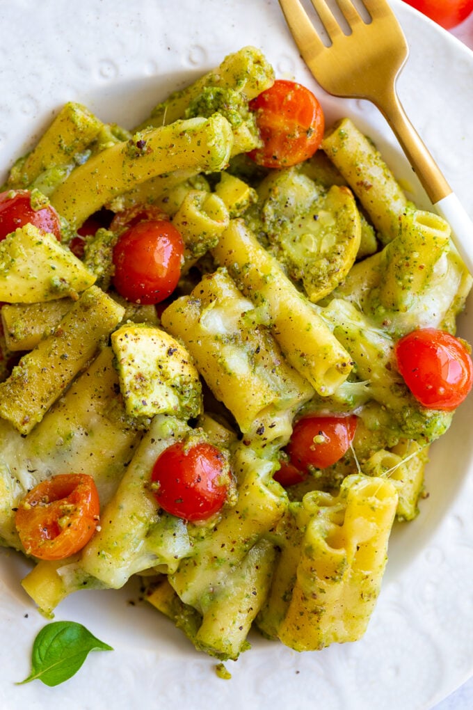 pesto pasta in a bowl mixed with yellow squash and cherry tomatoes