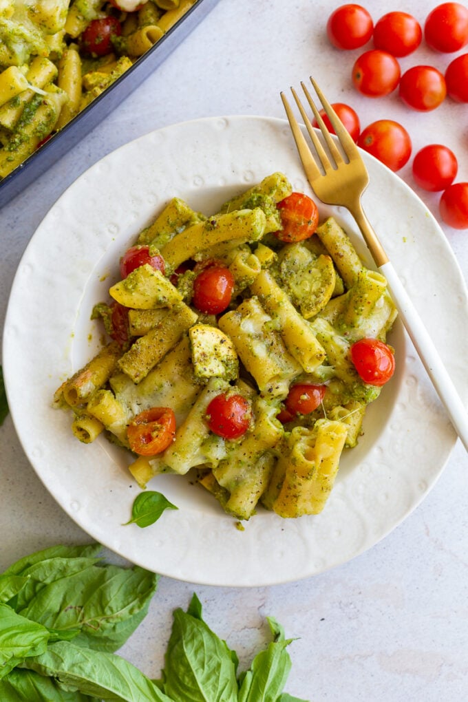 pesto pasta in a bowl mixed with yellow squash and cherry tomatoes