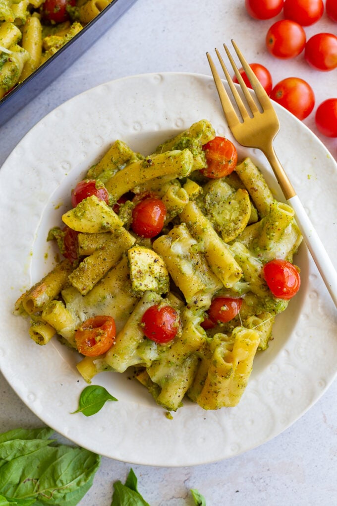 pesto pasta in a bowl mixed with yellow squash and cherry tomatoes