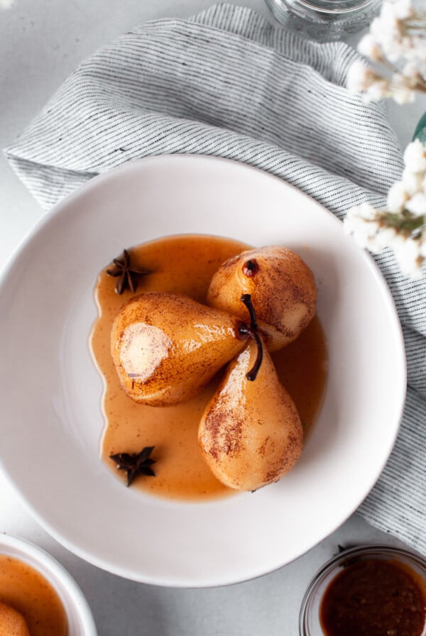 three poached pears in a small white bowl