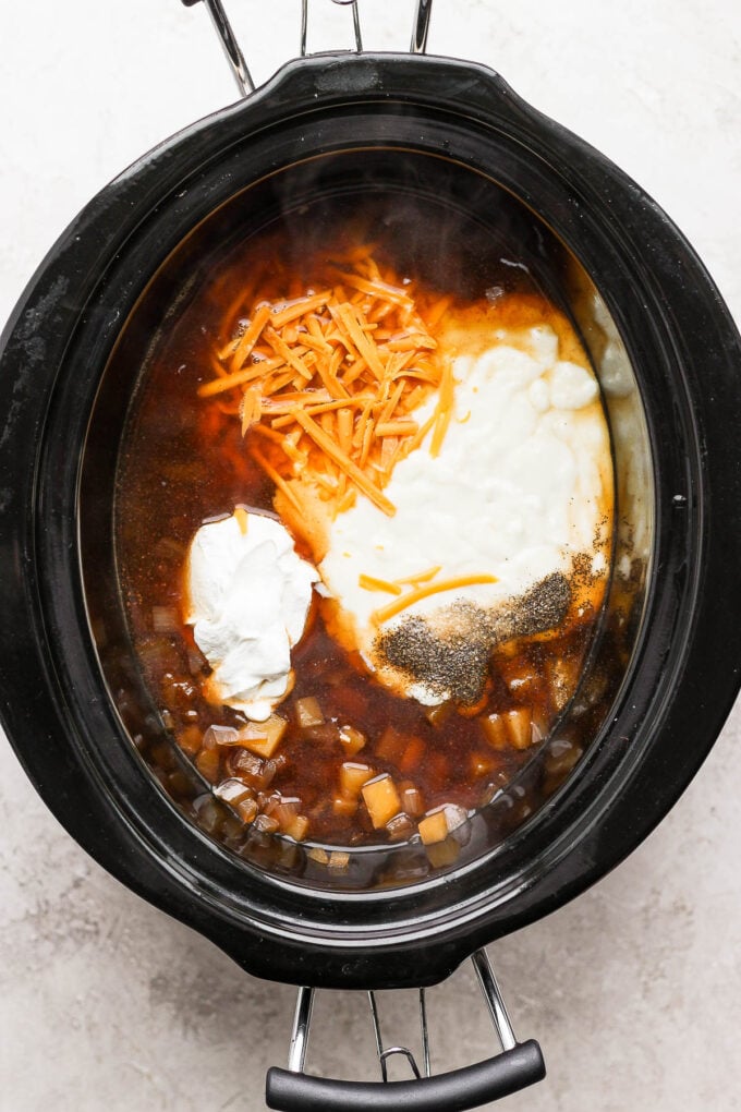 Adding sour cream and cheese to crockpot.