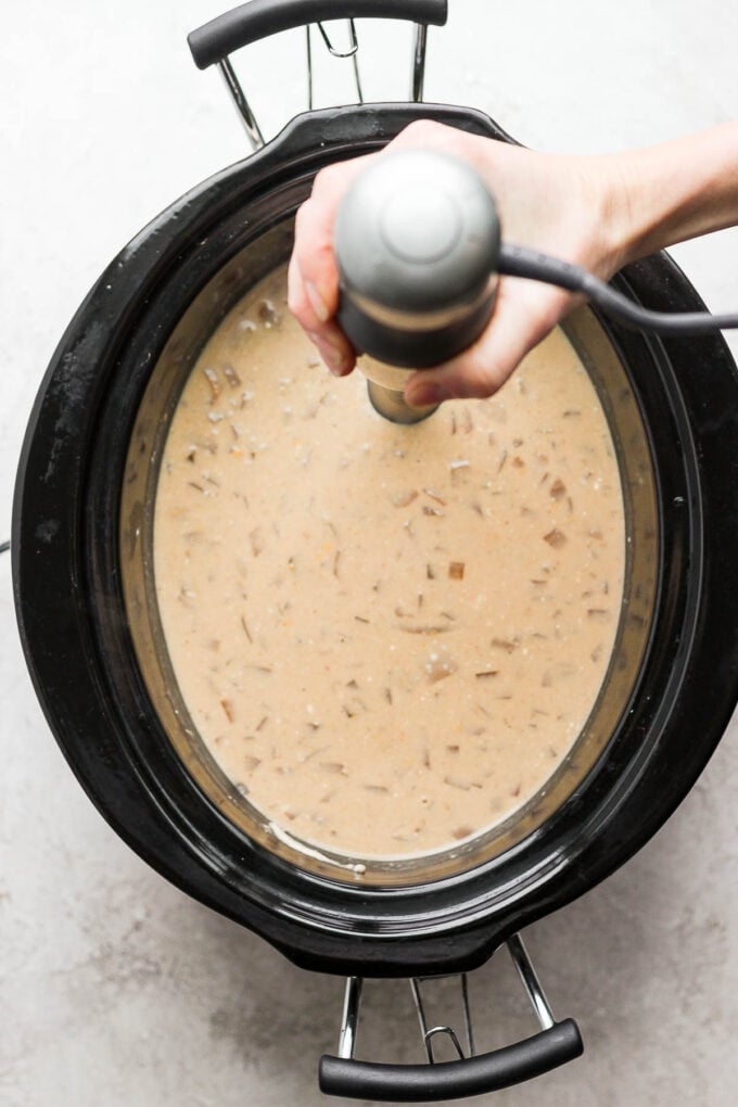 Using an immersion blender to blend potato soup.