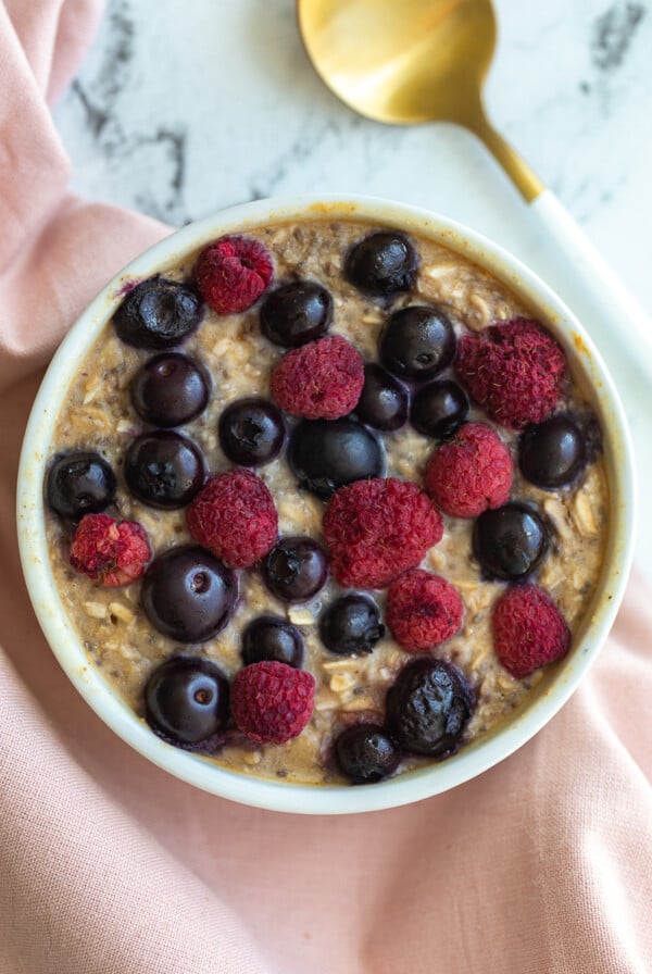 single serve baked protein oats in a ramekin and topped with fruit.