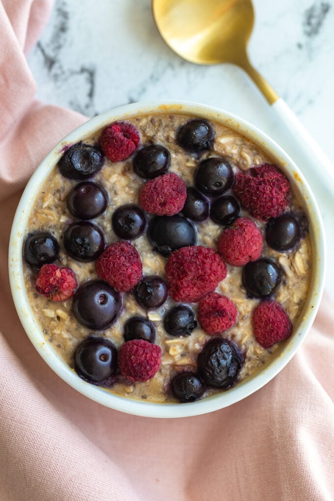 single serve baked protein oats in a ramekin and topped with fruit.