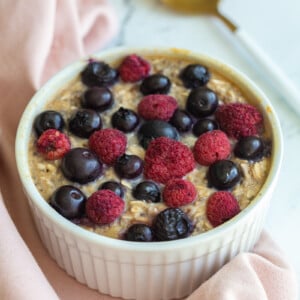 single serve baked protein oats in a ramekin and topped with fruit.