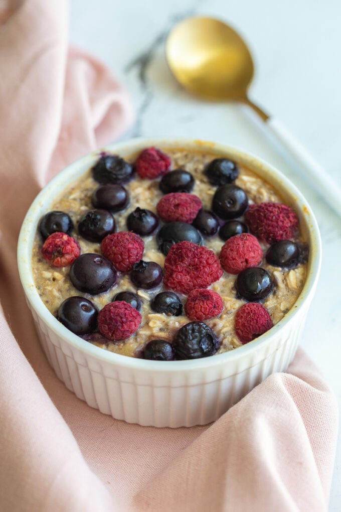 single serve baked protein oats in a ramekin and topped with fruit.