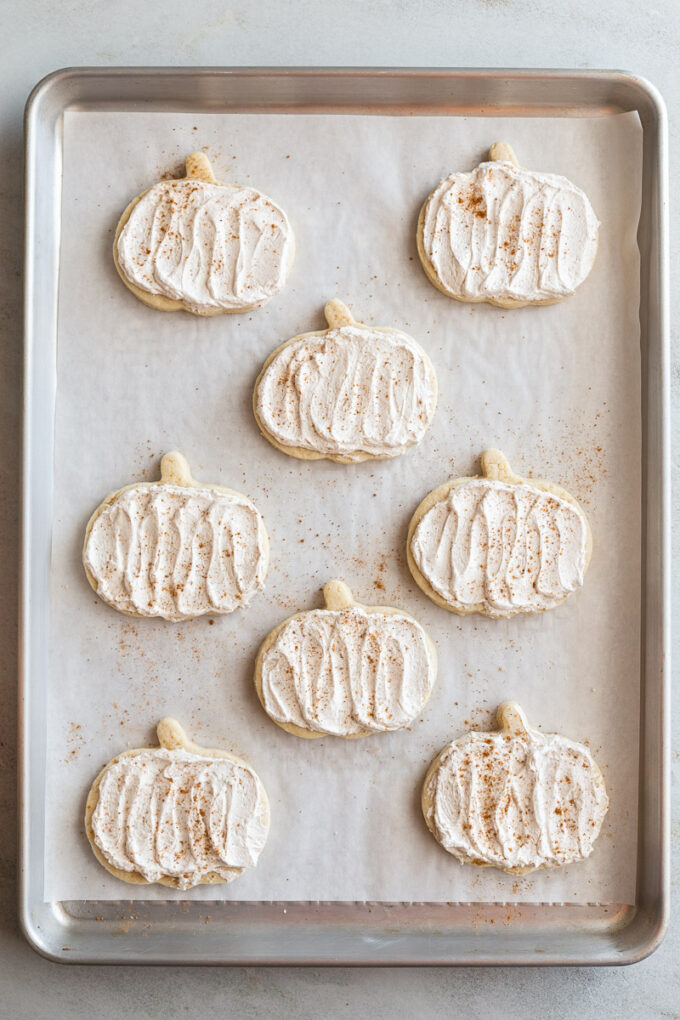 pumpkin shaped sugar cookies topped with a maple icing and sprinkled with nutmeg