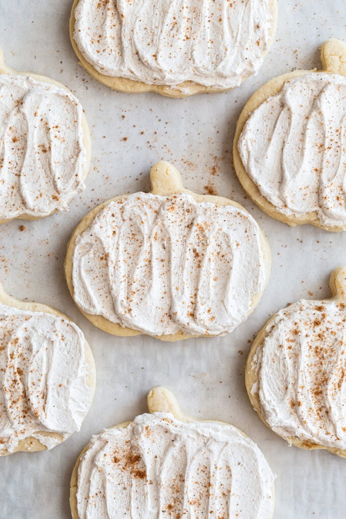 pumpkin shaped sugar cookies topped with a maple icing and sprinkled with nutmeg