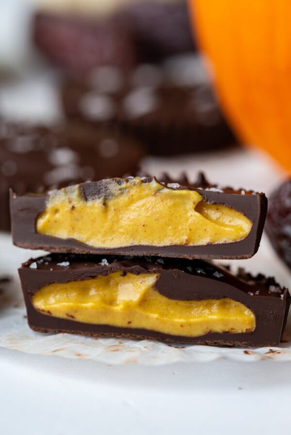 pumpkin peanut butter cup cut in half with a small pumpkin in the background