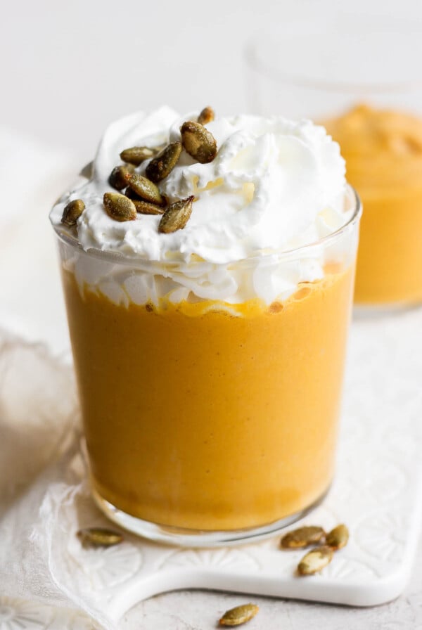 Pumpkin smoothie topped with whipped cream and pumpkin seeds.