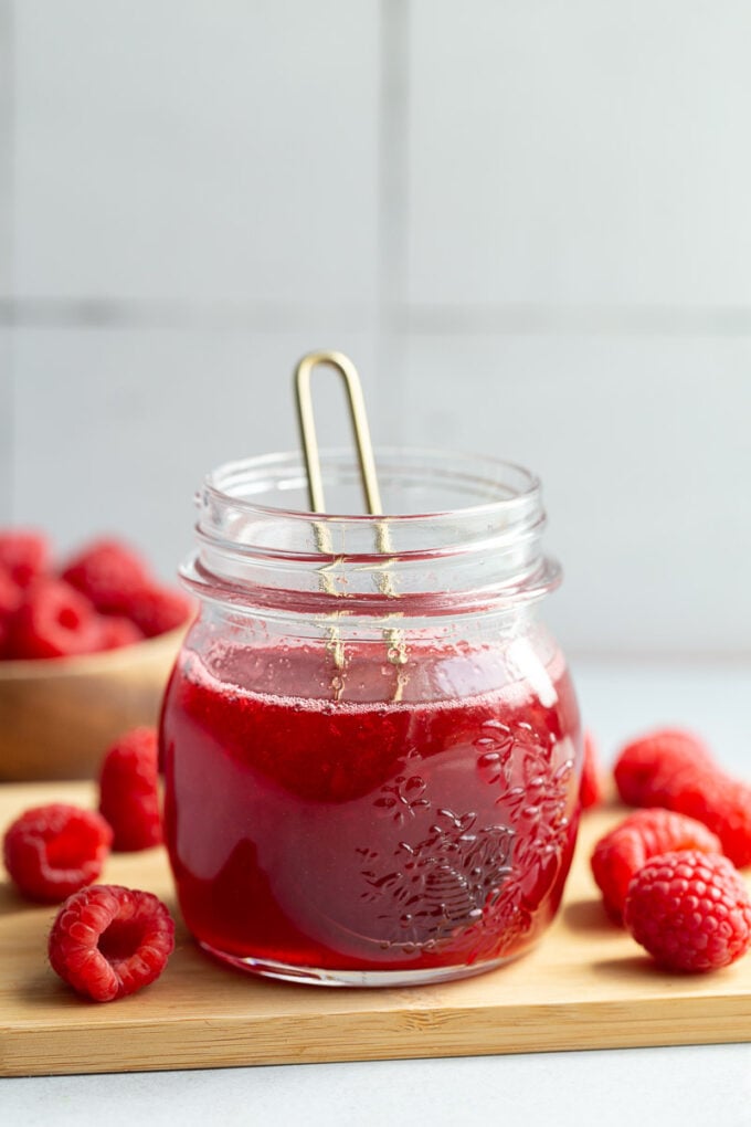 A small glass jar of raspberry simple syrup.