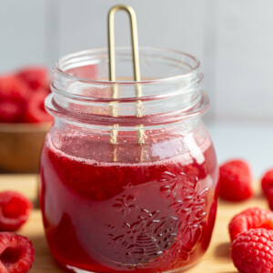 Raspberry syrup in a small glass jar.