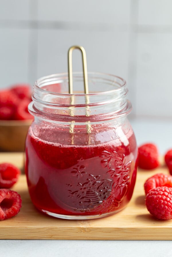 Raspberry syrup in a small glass jar.