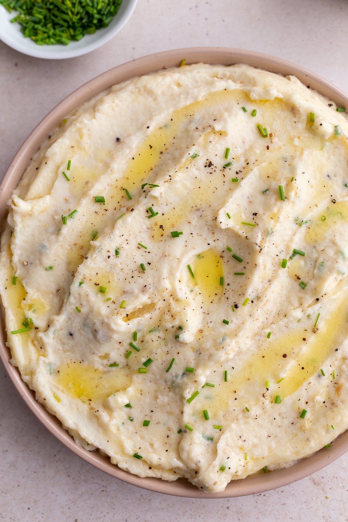 big pink bowl of roasted garlic mashed potatoes topped with diced chives