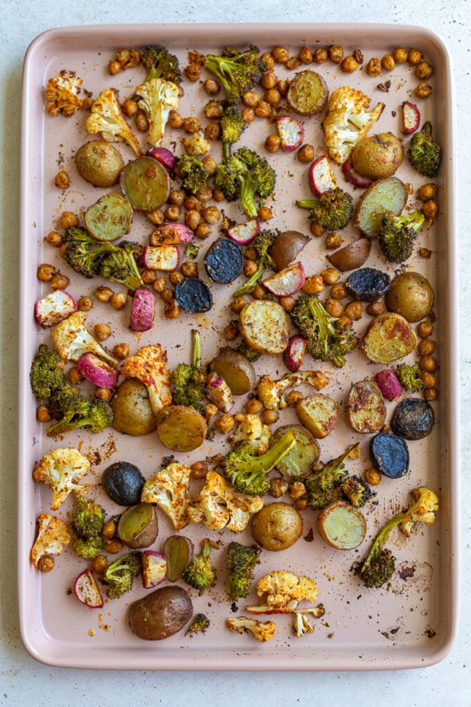 roasted veggies on a large baking tray: potatoes, radish, broccoli, and cauliflower