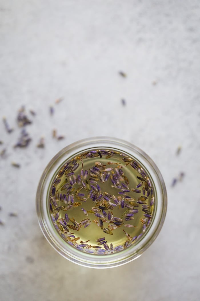 lavender simple syrup in a small glass jar. fresh lavender in it