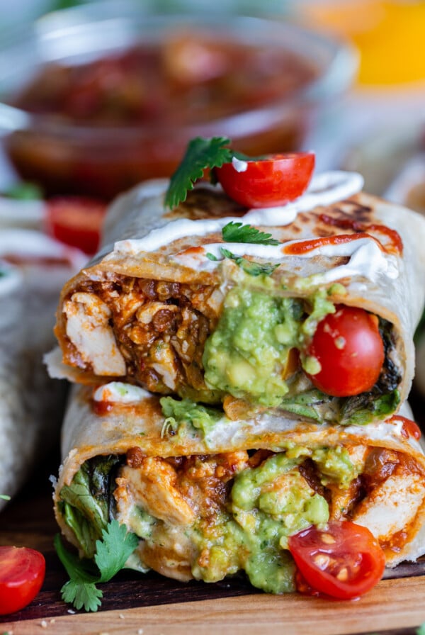 spicy tofu burrito cut in half and topped with cream and tomatoes