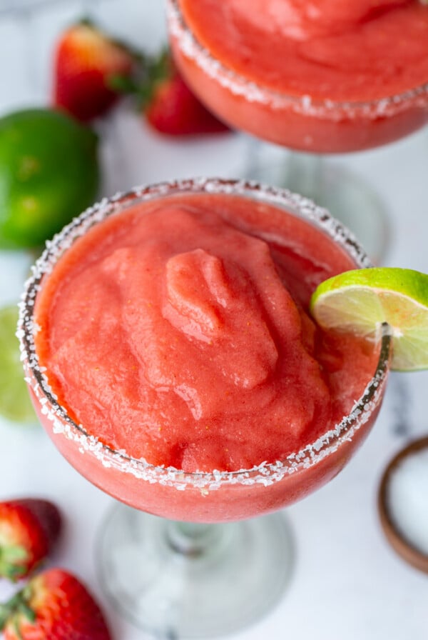 up close shot of a frozen strawberry margarita with a lime wedge on the side