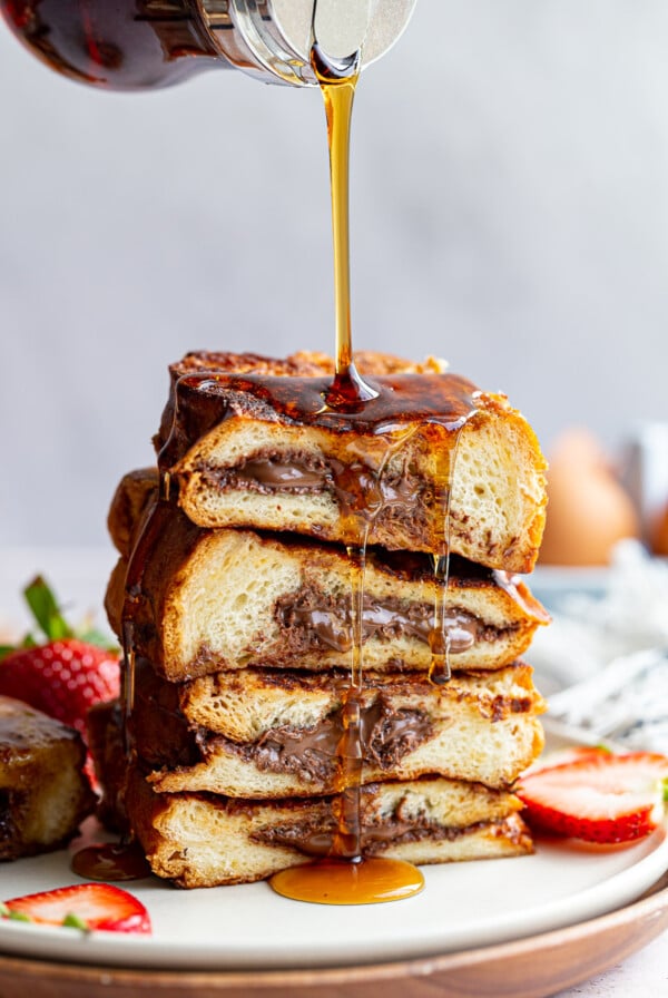 Drizzling syrup over a stack of Nutella stuffed French toast.