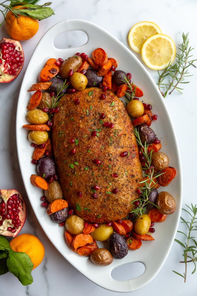 stuffed vegan roast surrounded by roasted veggies on a platter