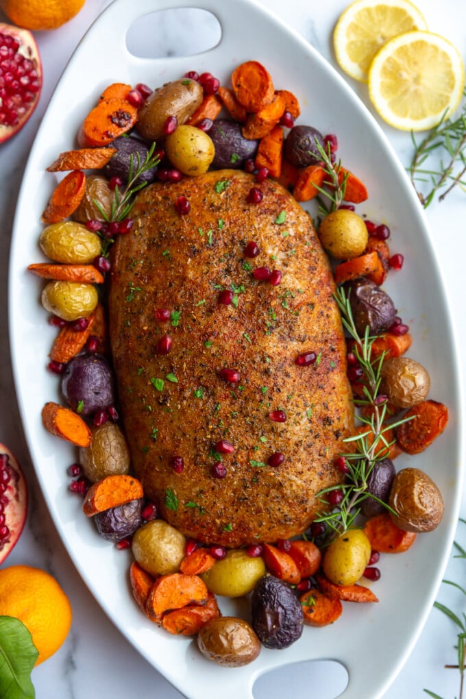 stuffed vegan roast surrounded by roasted veggies on a platter