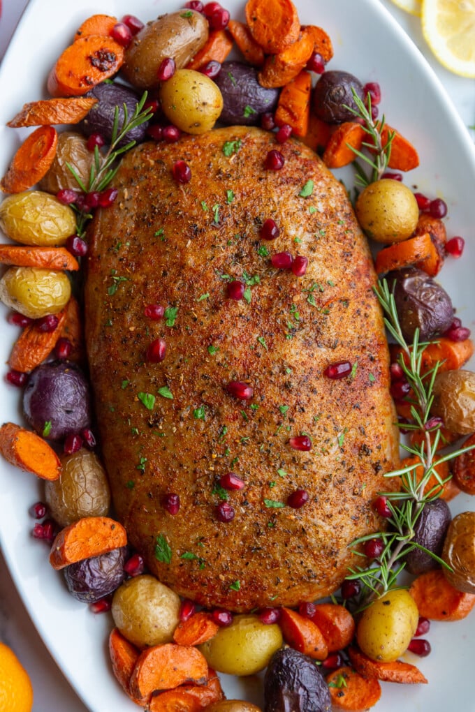 stuffed vegan roast surrounded by roasted veggies on a platter