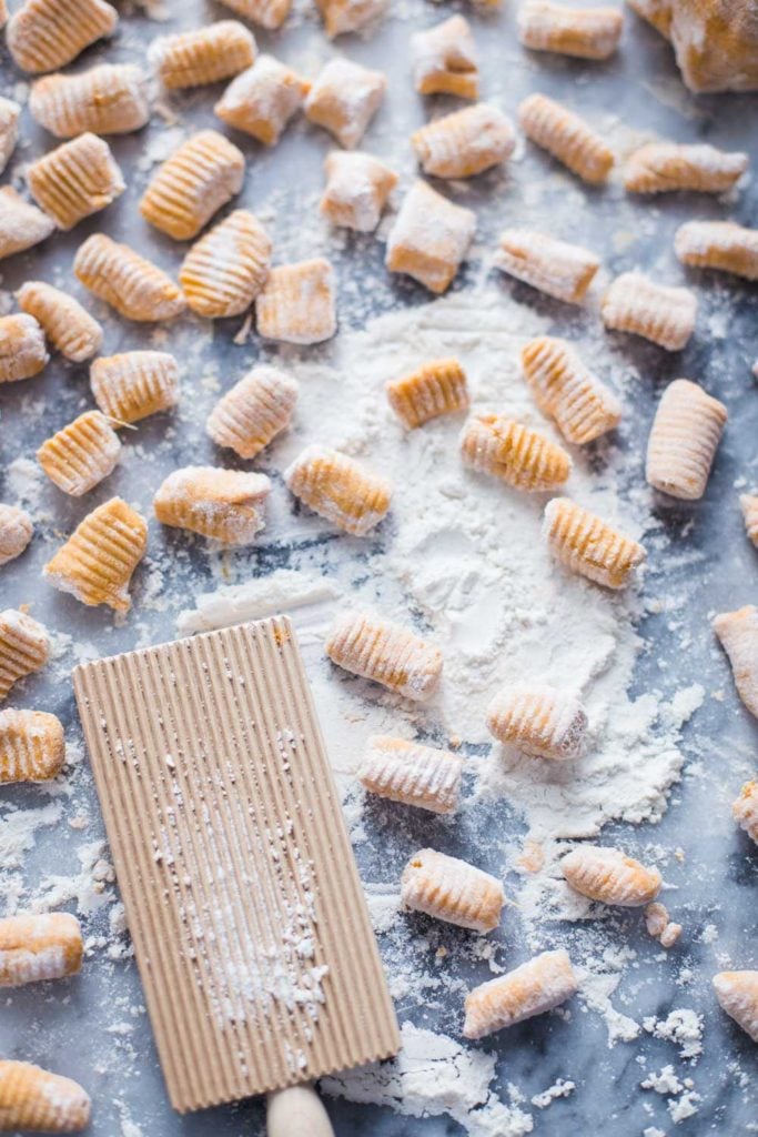 sweet potato gnocchi on a marble board with flour all around