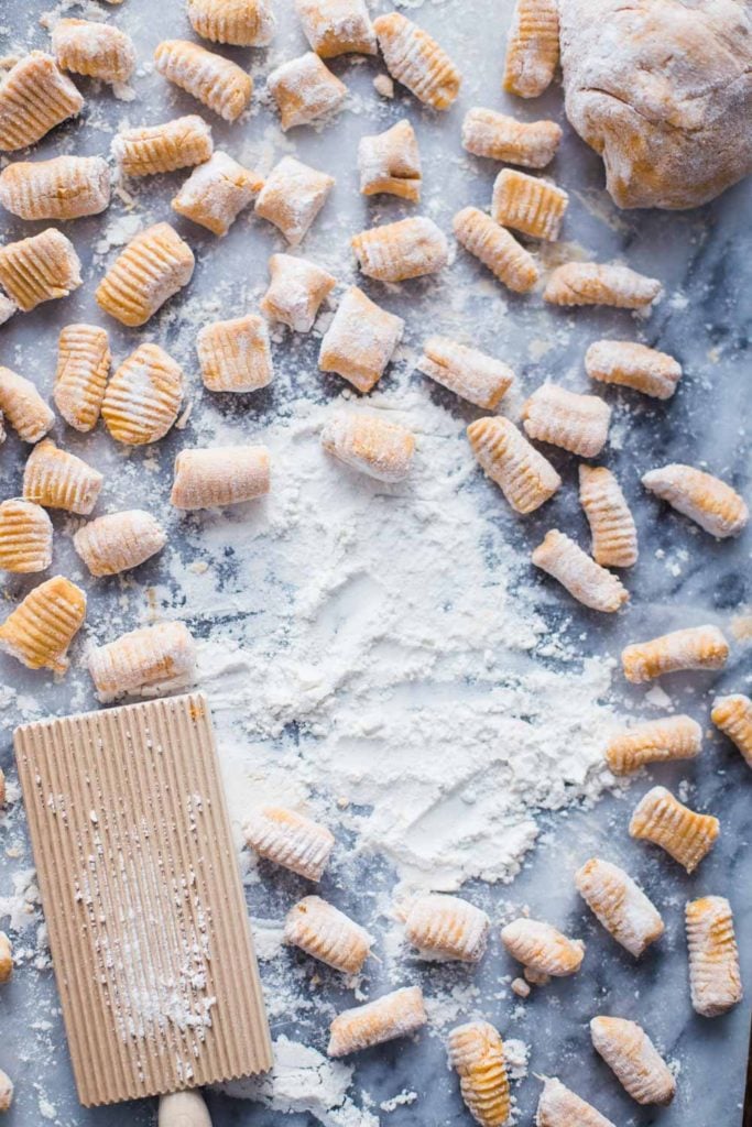 sweet potato gnocchi on a marble board with flour al around 