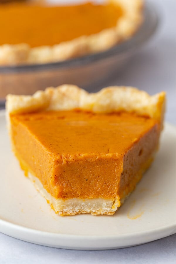 slice of sweet potato pie with a bite taken out and the rest of the pie in the background