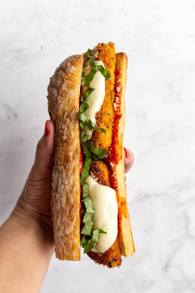 Woman's hand holding a Tofu Parmesan Sandwich.