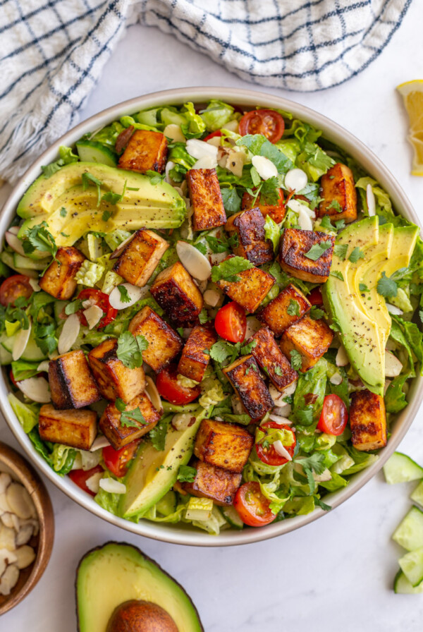 tofu salad topped with sliced avocado and cherry tomatoes