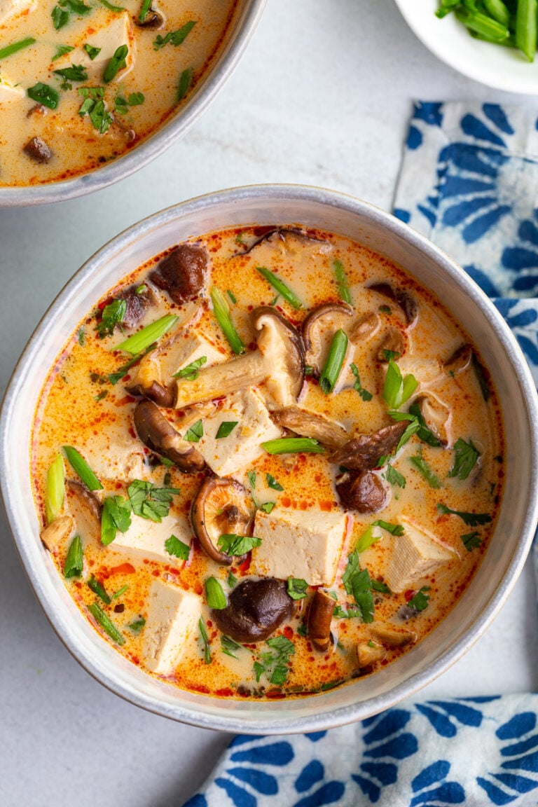 Soup made with tofu and mushrooms in a white bowl.