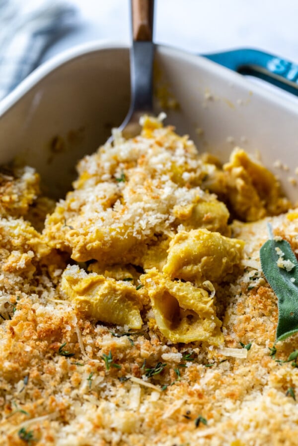 scoop of vegan mac and cheese toped with a breadcrumb mixture and fresh sage