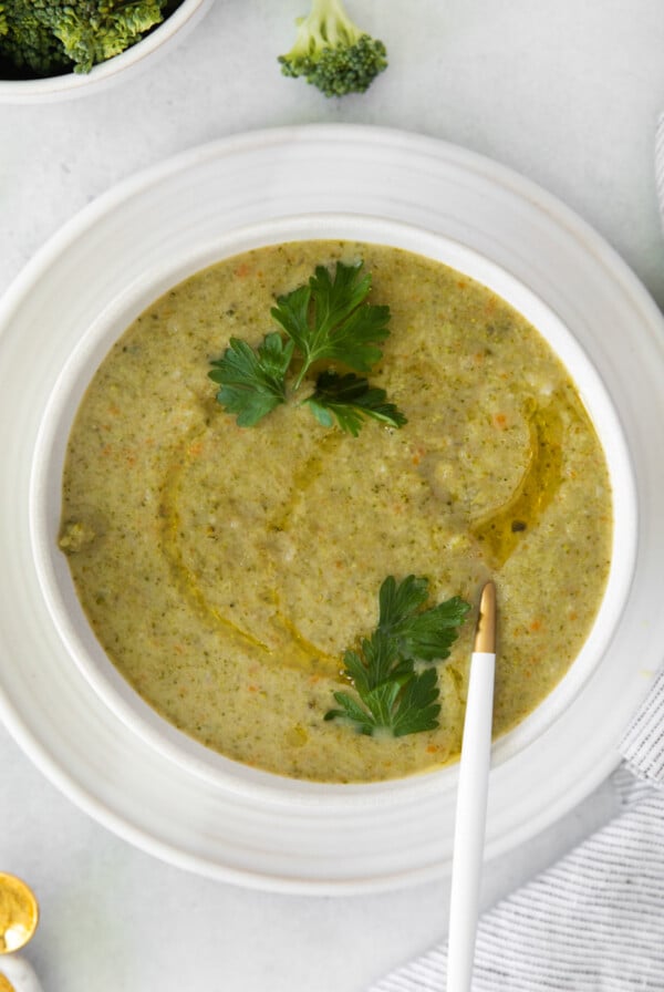 vegan broccoli soup served in a white bowl with a garnish of parsley