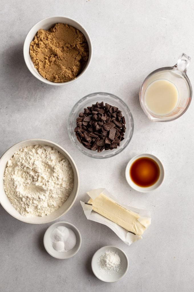 ingredients laid on a table for vegan chocolate chip cookies: brown sugar, flour, baking soda, salt, vegan butter, almond milk