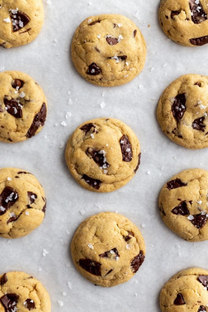 chocolate chip cookies lined up on a baking tray with a touch of flaky sea salt