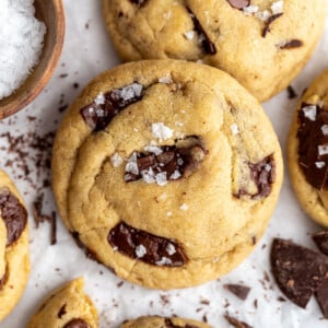 Vegan chocolate chip cookies stacked on top of each other and topped with a bit of flaky sea salt