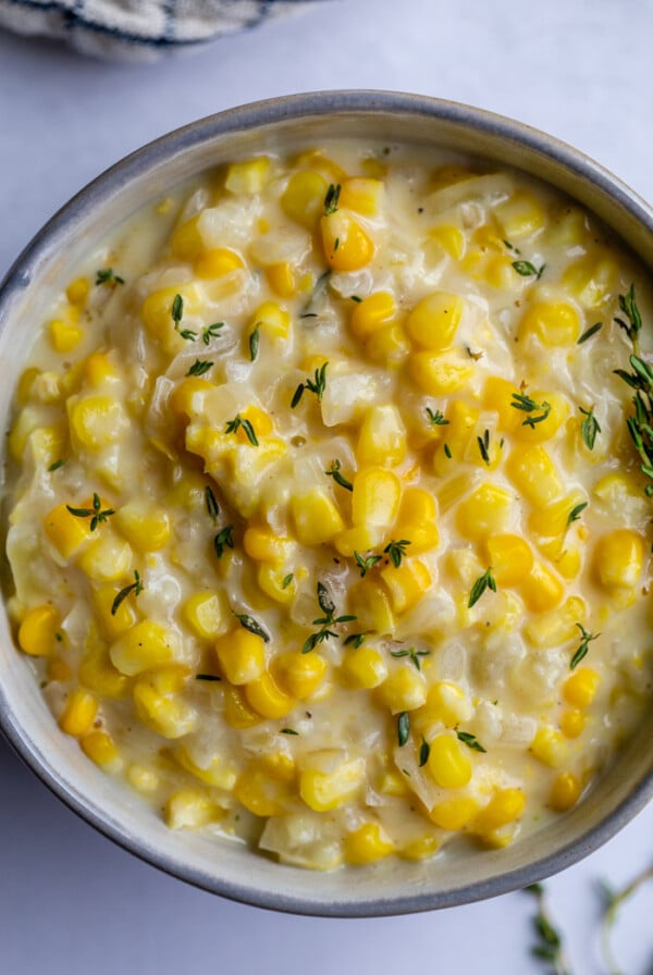 light blue bowl of creamed corn topped with fresh thyme