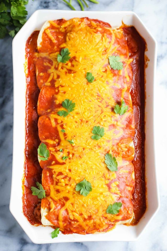 Casserole dish with freshly baked enchiladas and cilantro leaves sprinkled on top