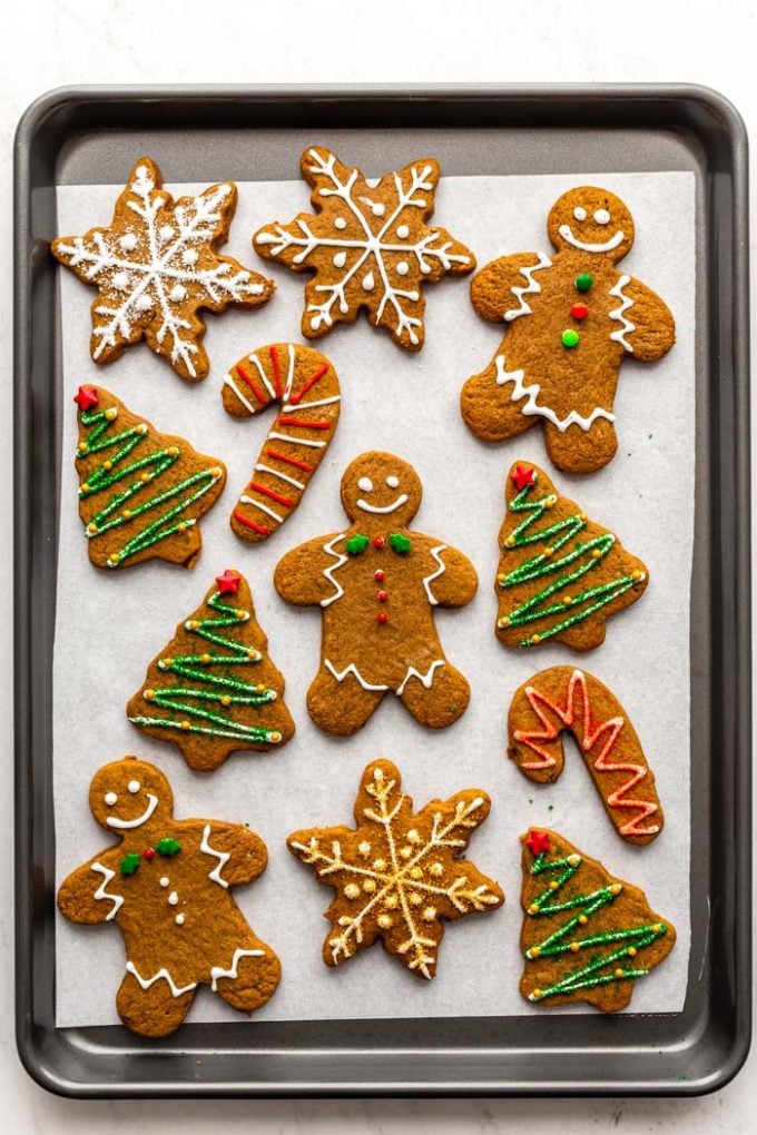 gingerbread cookies decorated with icing and sprinkles on a baking sheet