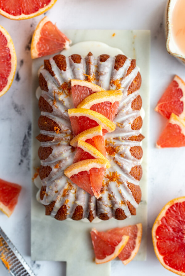 Iced grapefruit loaf topped with slices of grapefruit and more grapefruit around the loaf