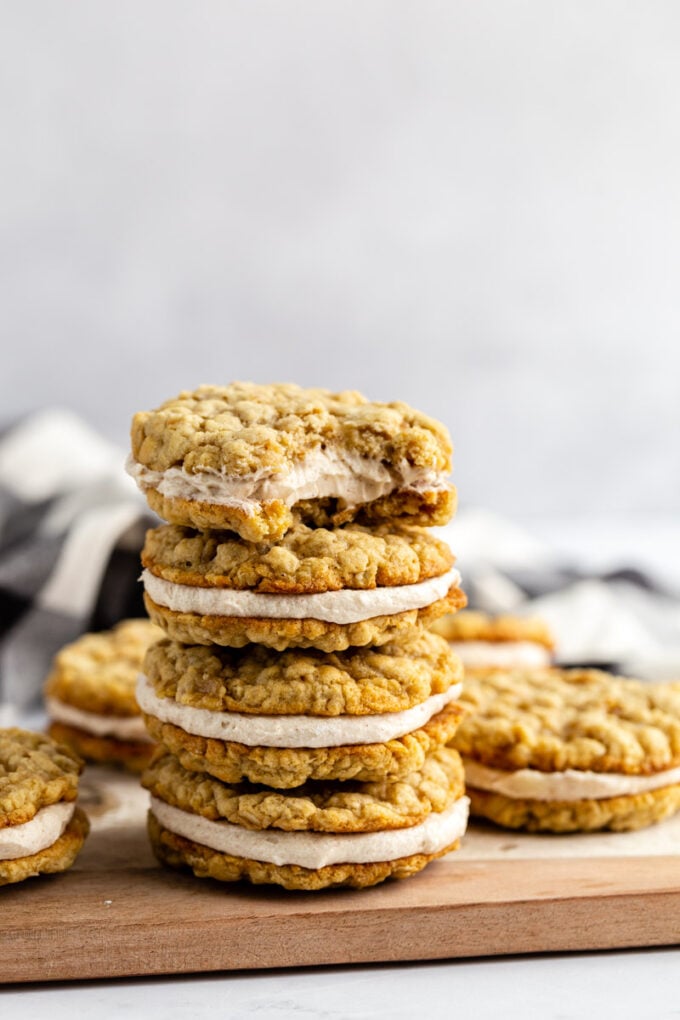 oatmeal cream pies stacked on top of each other on a wood and marble board. a bite taken out of the top cookie