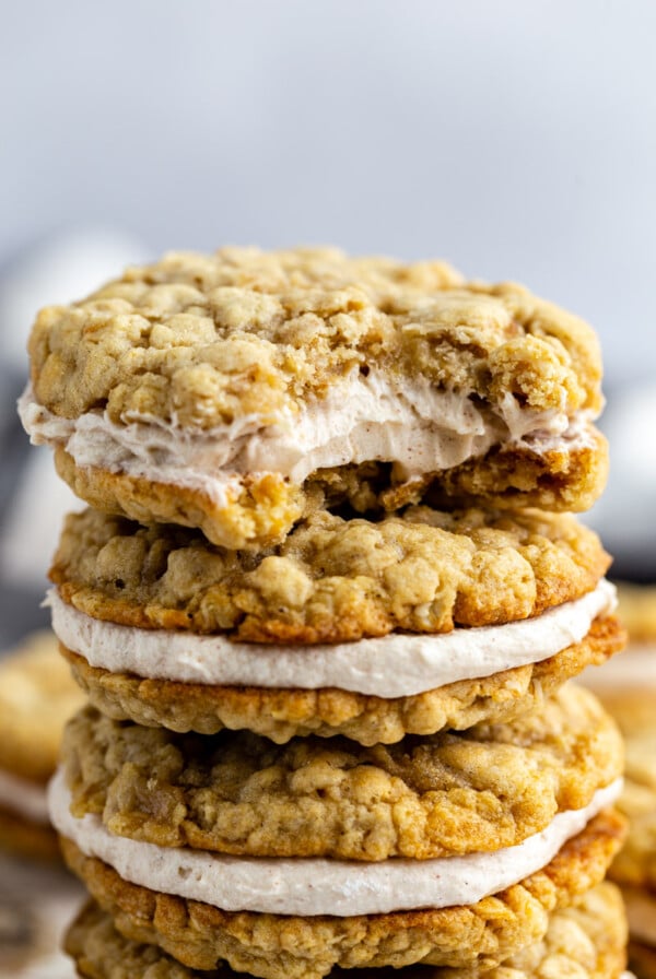 oatmeal cream pies stacked on top of each other on a wood and marble board. a bite taken out of the top cookie