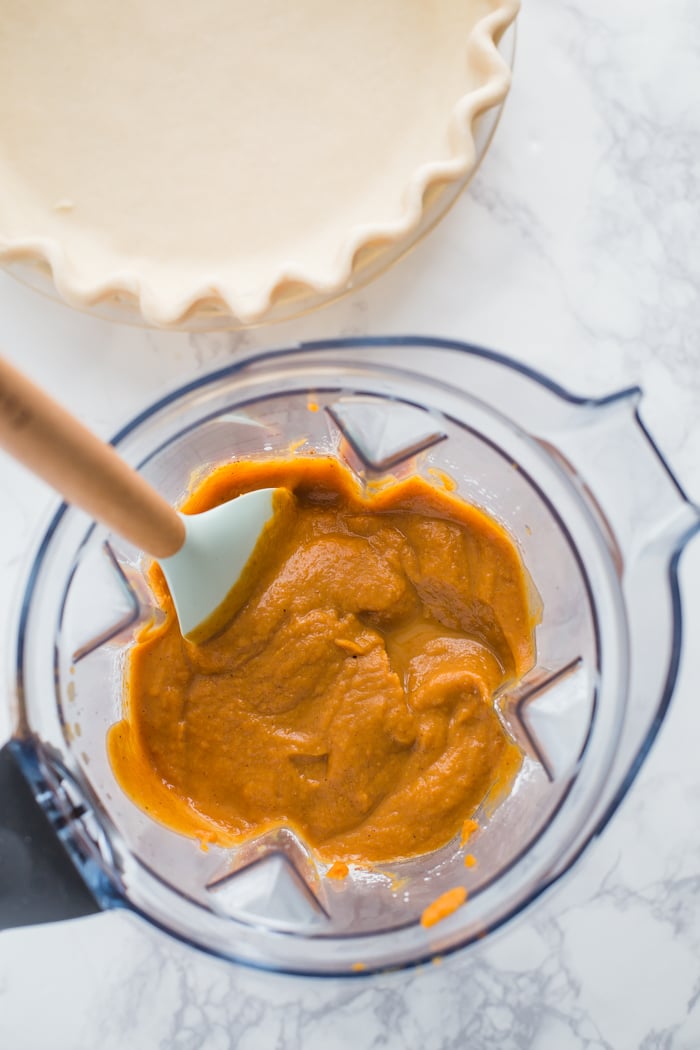 vegan pumpkin pie filling in a blender with a pie crust in the background