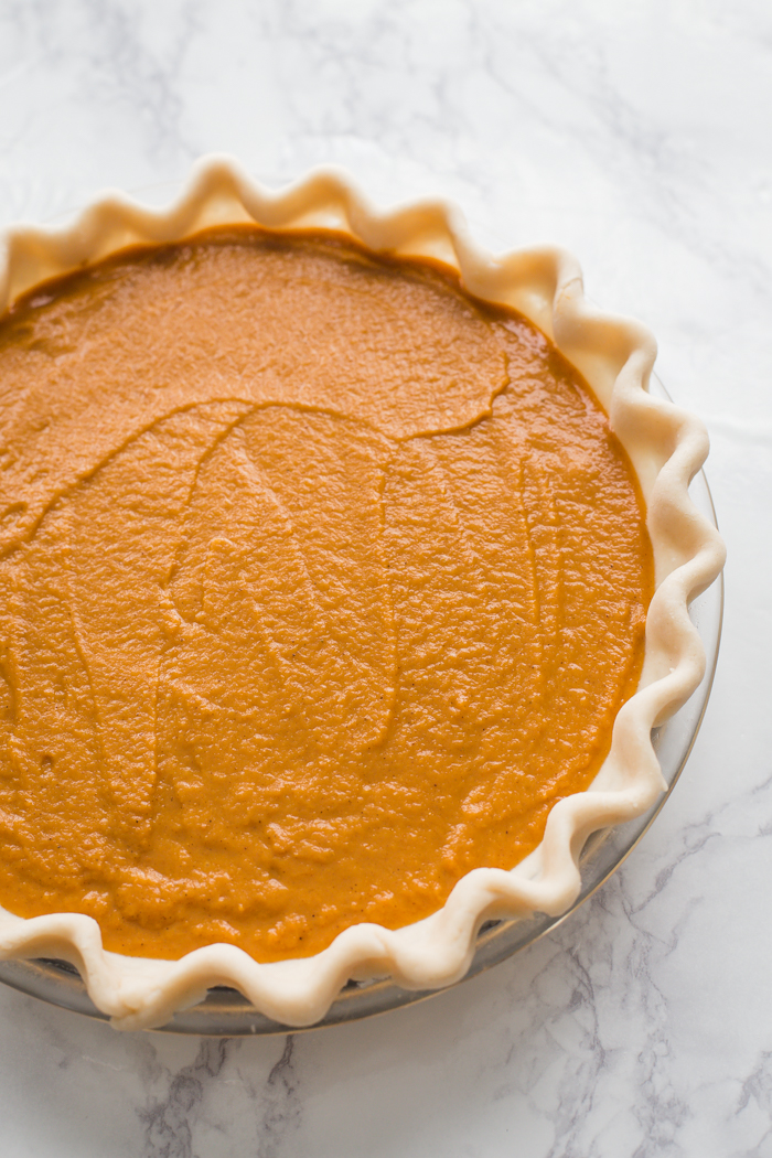 unbaked vegan pumpkin pie on a marble board