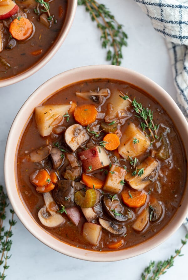 vegan stew served in a small white bowl with fresh thyme